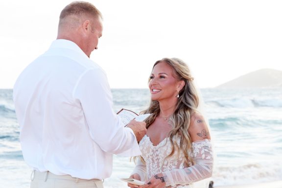 Sandy Beach Wedding Ceremony Bride and groom exchanging vows on a beach during sunset.