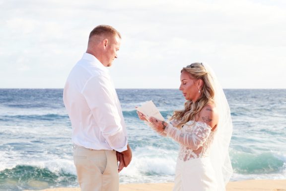 Sandy Beach Wedding Ceremony A bride and groom exchanging vows on a beach during a wedding ceremony.