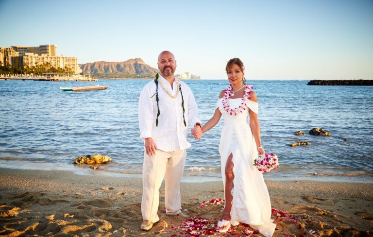 Hawaii Weddings at Makapuu Pt. Lookout A couple embraces on a rocky cliffside with a blue ocean and island in the background at Makapuu Pt. Lookout.